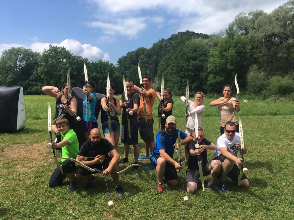 Groupe de personnes souriantes tenant des arcs d'archery tag dans un champ ensoleillé
